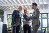 a woman and two men look at a clipboard